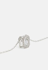 Collier en argent avec un pendentif en forme de rectangle, orné de petites pierres claires, attaché à une chaîne délicate.