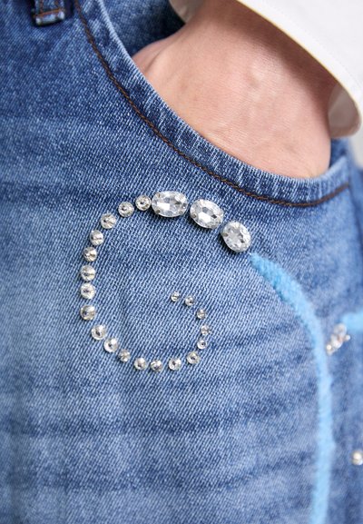 Denim-Jeans mit einem blauen Spiraldesign aus Strasssteinen auf der Tasche. Verfügt über einen traditionellen Fünf-Taschen-Stil und kontrastierende Nähte.