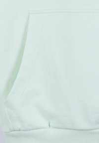 Tela de sudadera de un suave color verde menta claro con un bolsillo frontal y dobladillo acanalado, que presenta una textura suave y costuras planas.