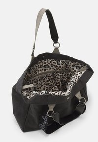 Zwarte canvas tas met een voering van luipaardprint, grijze gestructureerde hengsels, een ritsvak aan de binnenkant en een drukknoopsluiting. Bevat metalen hardware.