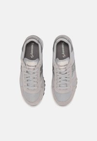 Grijze sneakers van mesh en suede materiaal, ronde neus, vetersluiting en subtiele branding op de tong. Rubberen buitenzool met grip.