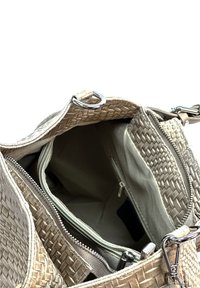 Beige gehaakte handtas met een open hoofdcompartiment, zichtbaar ritsvak aan de binnenkant en zilveren metalen sluitingen op de handvatten.