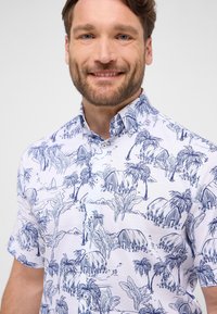 Korte mouw shirt van wit stof met een tropisch print in blauw, featuring palmbomen, strand elementen en omtrekdetails. Met knoopsluiting op de kraag.