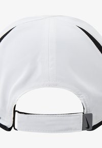 Gorra blanca con detalles en negro y una correa trasera ajustable. Presenta una textura suave y mate con detalles cosidos y una pequeña etiqueta con el logo.