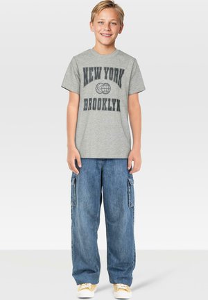 Grå bomulls T-skjorte med "NEW YORK BROOKLYN" grafikk, kombinert med blå denim cargo-bukser med sidelommer og gule sneakers.