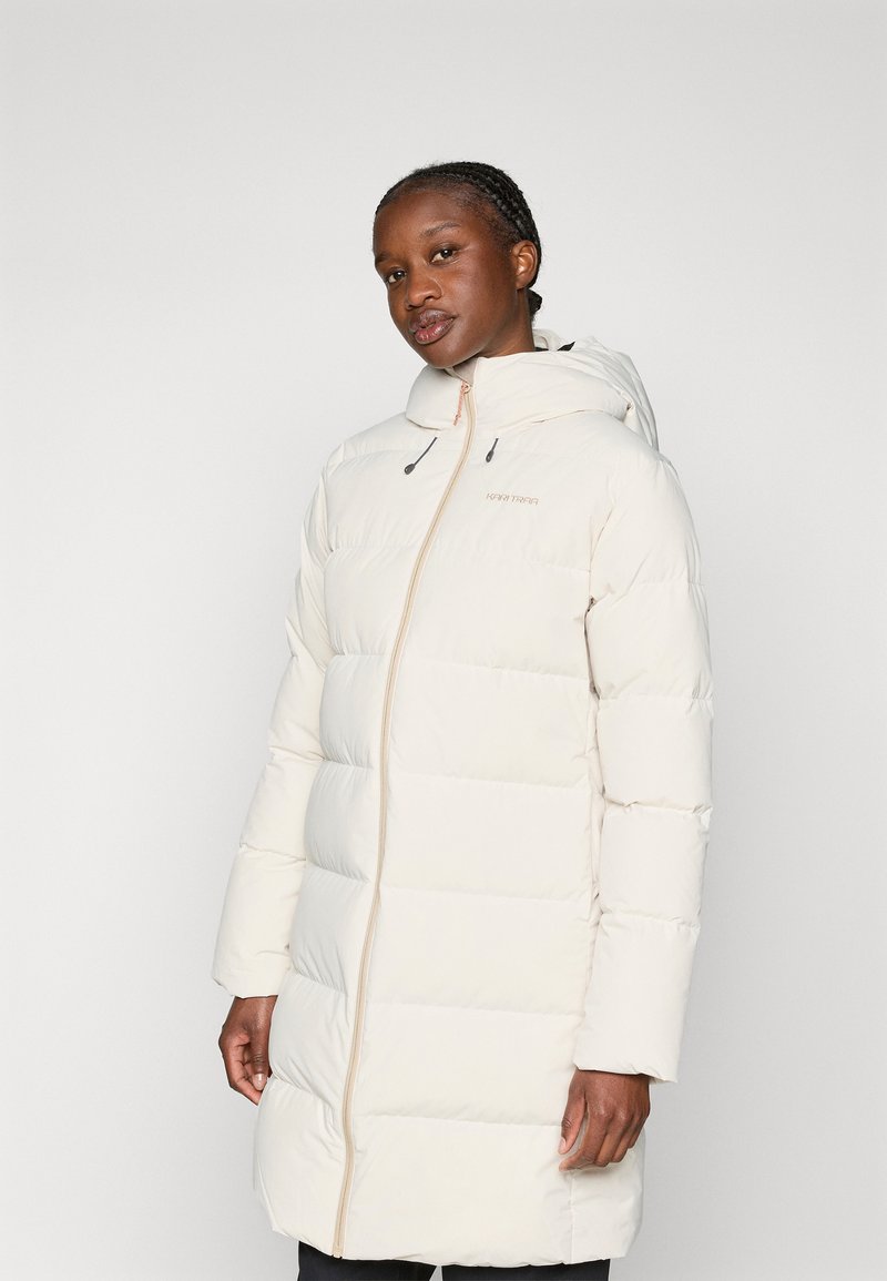 Kurtka puchowa w kolorze kremowym z zamkiem z przodu, kapturem i przeszywanymi panelami. Posiada sznurki przy kapturze oraz dyskretną naszywkę z logo na klatce piersiowej.
