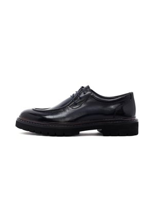 Zapato de cuero negro con cordones, suela gruesa de goma negra y puntera redondeada, mostrado de perfil sobre fondo blanco.
