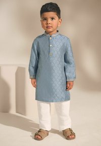 Lichtblauwe etnische kurta met een gestructureerd ruitpatroon, gouden knopen en decoratieve manchetten, gecombineerd met witte broeken en bruine sandalen.