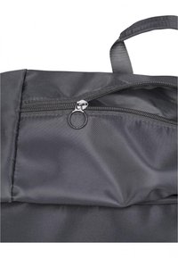 Sort nylon taske med en lynlåslukning, der har et stofhåndtag og en glat, struktureret overflade. Lynlåsens trækstang er sølvfarvet.