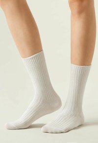 Calcetines de crew blancos con relieve, fabricados en un material suave, que presentan un ajuste elástico cómodo en la parte superior y una puntera reforzada para mayor durabilidad.