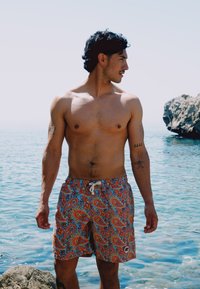 Korta badbyxor med ett flerfärgat paisleymönster, med dragsko i midjan, tillverkade av lättviktig tyg, perfekta för vattenaktiviteter.