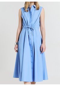Jasnoniebieska sukienka zapinana na guziki z dopasowaną talią i detalem w postaci wiązania. Bez rękawów, z luźną spódnicą i gładką teksturą materiału.