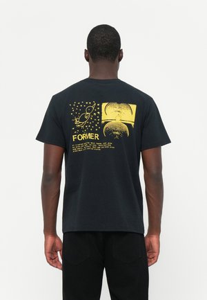 Black cotton t-shirt featuring yellow printed graphics, including a rocket, stars, and the word "FORMER." Short sleeves, standard fit.