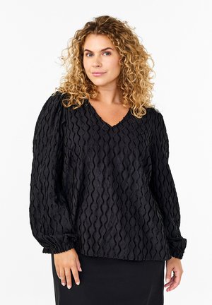 Sort bluse lavet af tekstureret stof med bølgede mønstre, V-hals, elastiske ballonærmer og afslappet pasform. Designet til komfort og stil.