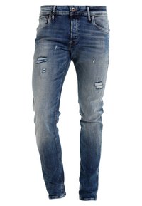 Rifle s úzkým střihem z světle modrého denimu, s opranými a roztrhanými detaily. Design s pěti kapsami a zapínáním na knoflík.