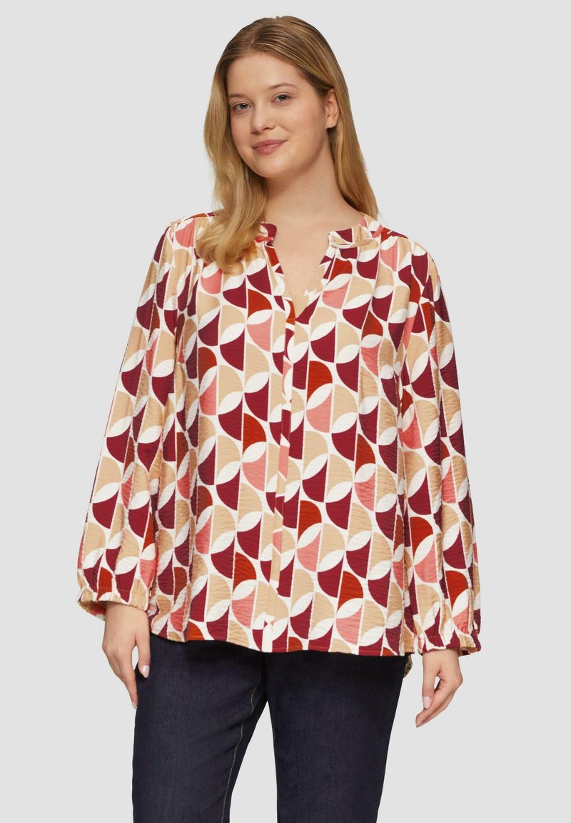 Blouse met lange mouwen van lichtgewicht stof met een geometrisch patroon in roest, crème en perziktinten; heeft een mandarinnekraag en knoopsluiting.