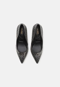 Ballerines noires à bout pointu avec des accents cloutés. Tige en cuir lisse avec une finition brillante. Doublure intérieure douce. Logo ALDO visible à l'intérieur.