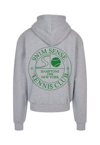 Pelēks krekls ar kapuci, kuram ir apaļa zaļa grafika ar uzrakstu "9N1M SENSE", tenisa bumbu un tekstu "TENNIS CLUB". Mīksta auduma ar kabatu.