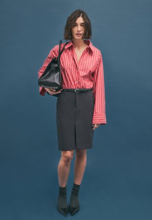 Raudonai ir balta juostelėmis marškiniai, juodas pieštuko sijonas su priekinėmis pjūvėmis, juoda odinė rankinė ir juodi smailiakulni batai su raštuotomis kojinėmis.