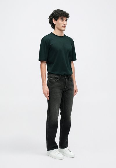 Un tricou negru cu guler rotund, combinat cu blugi gri închisi și adidași albi. Întreaga ținută are o croială lejeră și este confecționată dintr-un material moale și neted.