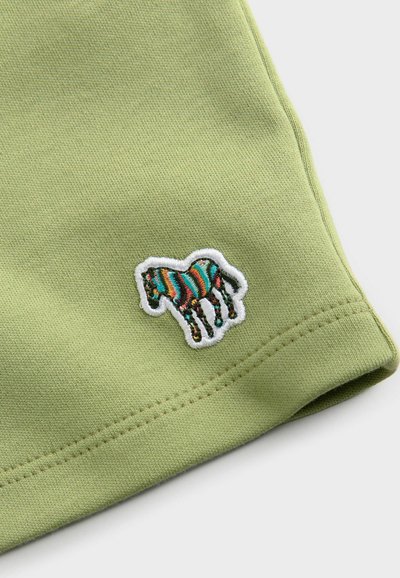 Grüner Baumwollstoff mit einem weißen gestickten Patch eines gestreiften Pferdes in Blau, Rot und Gelb. Glatte Textur mit genähten Kanten.
