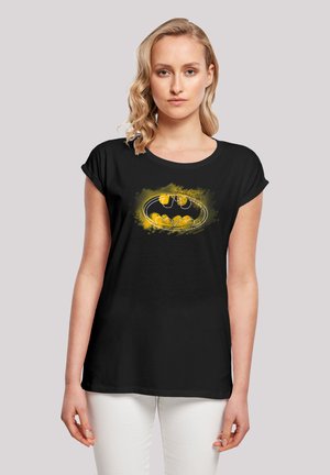 Black short-sleeve t-shirt featuring a yellow Batman logo and splatter design. The fabric is soft, with a relaxed fit and round neckline.