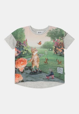 Chaton en rollers regardant un papillon, écureuils jouant au badminton, fleurs et un panneau « Merci de jouer sur l’herbe » sur un t-shirt gris.
