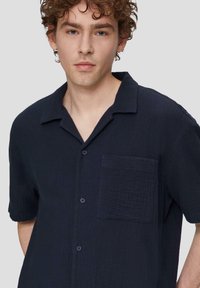 Marineblauw kortemouwenshirt van gestructureerde stof, met een knoopsluiting aan de voorkant, een borstzak en een ontspannen kraag.