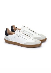 Witte sneakers met zwarte leren accenten en een rubberen zool. De bovenkant heeft een mix van gladde en suede texturen met duidelijke stikdetails.