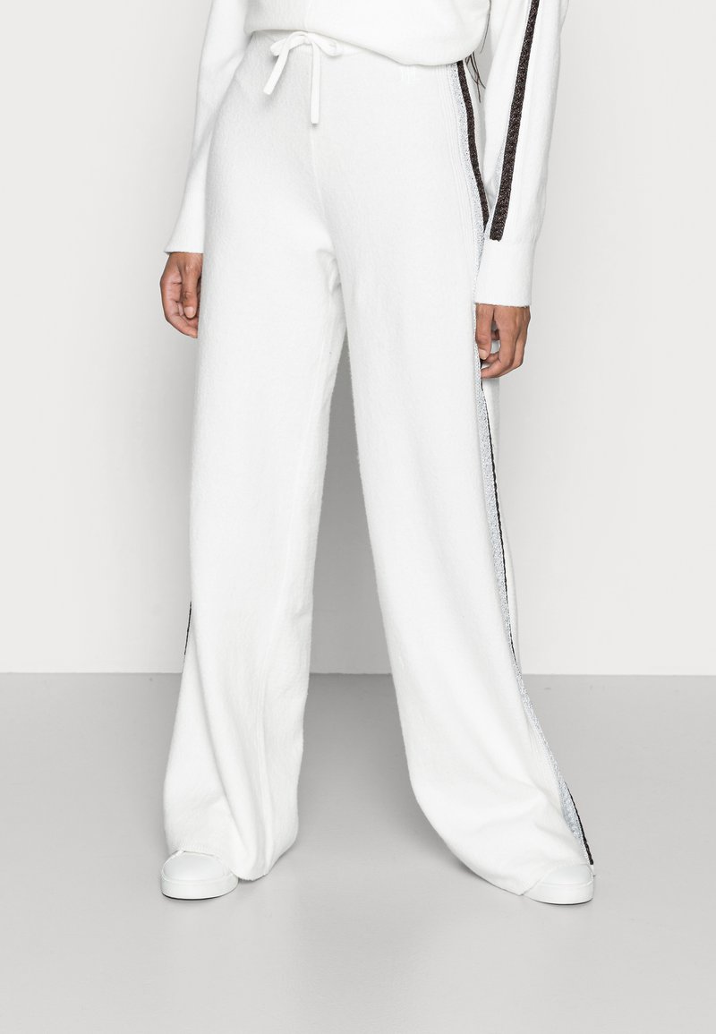 White wide-leg trousers made of soft, textured fabric. Features side stripes with a metallic sheen and an elastic waistband with drawstring.