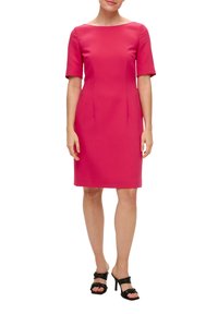 Robe rose ajustée avec un décolleté bateau et des manches courtes, dotée de deux pinces à l'avant. Portée avec des sandales à talons noires. Texture lisse.