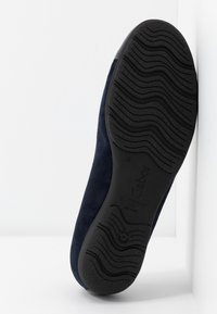 Une seule chaussure en daim bleu marine, avec la semelle face à l'avant, dotée d'un relief en caoutchouc noir. Le nom de la marque Gabor et "Homecraft" sont visibles sur la semelle.