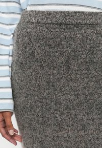 Neulottu harmaa hame, jossa on tekstuurinen ilme, korkea vyötärö ja hienovaraisia pinkkejä väripilkkuja. Yhdistetty vaaleansiniseen raidalliseen paitaan.