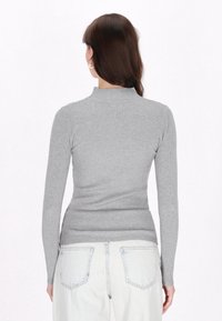 Grauer gerippter Rollkragenpullover mit langen Ärmeln, der sich durch ein figurbetontes Design und eine weiche Textur auszeichnet. Die Rückansicht zeigt subtile Nähte und eine raffinierte Schneiderkunst.
