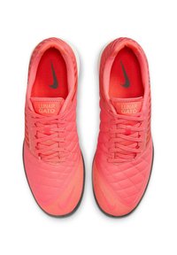 Rozā sintētiskie futbola apavi ar dimanta formas tekstūru, ar melnu Nike zīmi, plakaniem šņorēm un "Lunar Gato" uzlīmi.