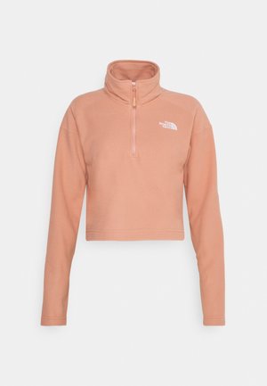 Jasnoróżowa krótka bluza z polaru z długimi rękawami, zamkiem do połowy, stójką i białym logo The North Face na lewej piersi.