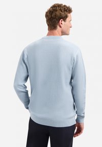 Lichtblauw geribbeld trui, zachte textuur, lange mouwen, ronde hals, aangesloten manchetten en zoom, casual pasvorm, gedragen met donkere broek.