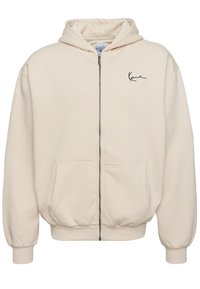 Bézs zipzáras kapucnis pulóver elülső zsebekkel, kapucnival, bordás mandzsettával és szegéllyel, valamint kis fekete logóval a bal mellrészen.