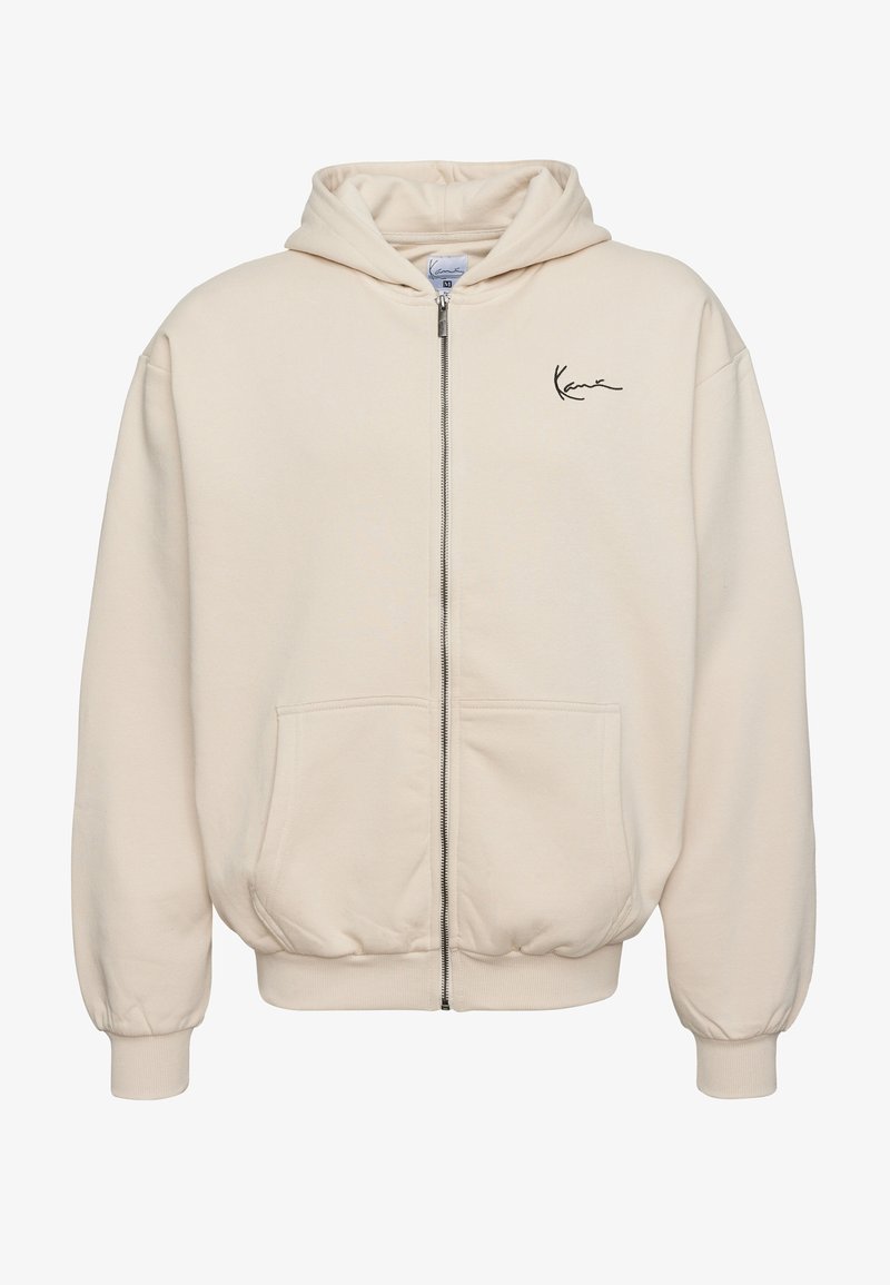 Bézs zipzáras kapucnis pulóver elülső zsebekkel, kapucnival, bordás mandzsettával és szegéllyel, valamint kis fekete logóval a bal mellrészen.