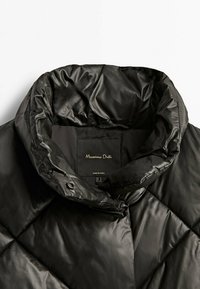 Sort, quiltet puffjakke med høj krave. Glat, blankt materiale. Etiketten indeni siger "Massimo Dutti" med størrelses- og plejeinformation.