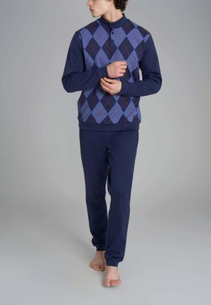 Completo loungewear blu navy composto da un pullover con un motivo di rombi blu, rossi e bianchi, abbinato a pantaloni blu navy uni. Vestibilità morbida e casual.