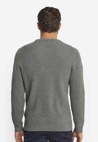 Grå ribbad tröja med långa ärmar, tillverkad av mjukt tyg. Har rund halsringning och en strukturerad mönster över ryggen.