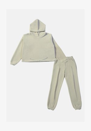 Svetlo bež flis pulover s kapuco in sprednjim vezanjem, v kombinaciji z usklajenimi tapered flis hlačami. Mehka, strukturirana tkanina.