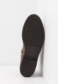 Braunes Leder-Schuh mit einer strukturierten schwarzen Gummisohle. Die Sohle weist ein Zickzackmuster auf und hat die Größe "37" eingraviert.