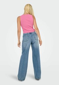 Top a righe rosa abbinato a jeans larghi azzurri chiari, con vita alta e tasche posteriori visibili. Design semplice e casual.