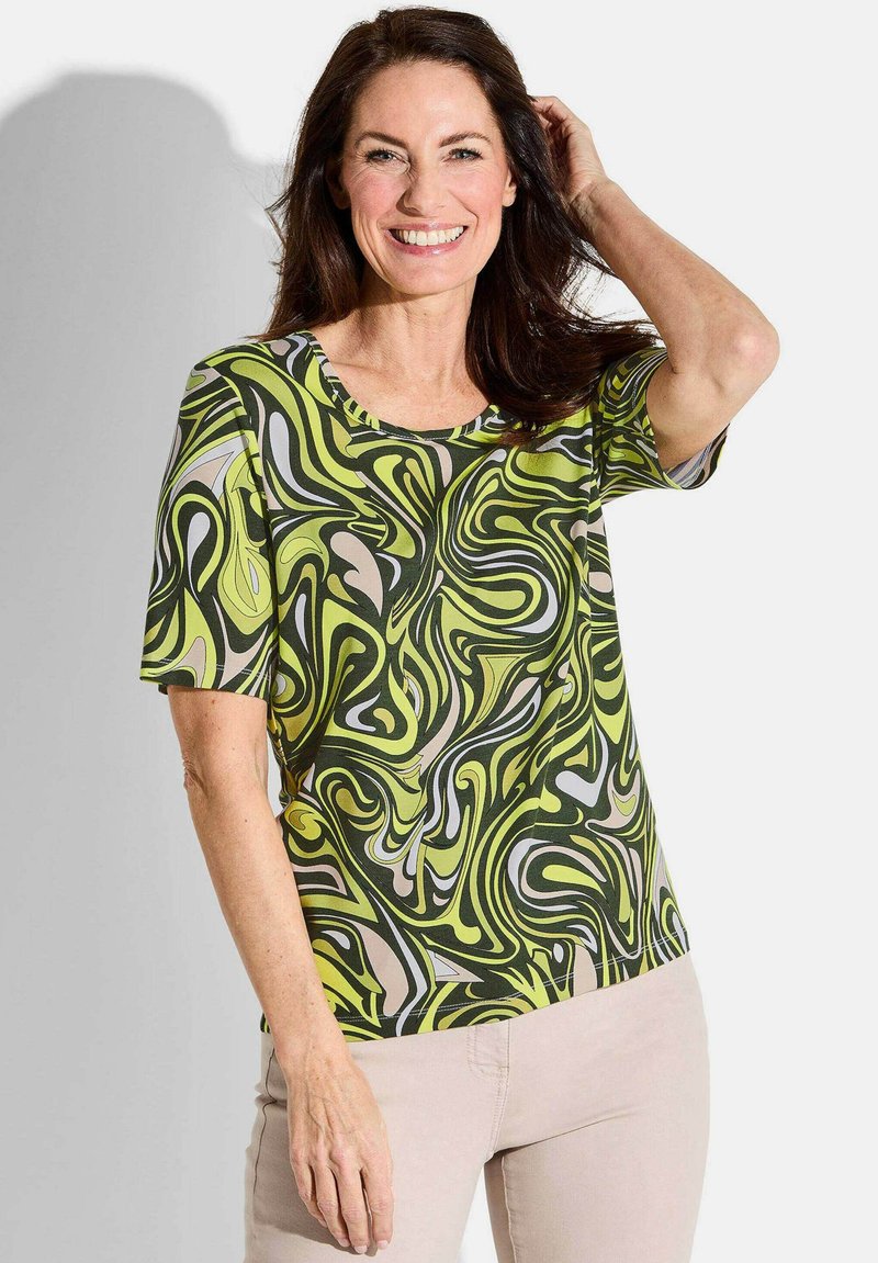 Korte mouwen blouse met een groen, geel en beige abstract draaipatroon, met een ronde halslijn en een zachte stoftextuur.