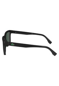 Lunettes de soleil noires avec des verres teintés en vert. Monture rectangulaire, accents texturés noirs sur les branches et un petit logo Lacoste.
