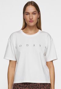 T-shirt bianco in cotone con colletto tondo e maniche corte, con il testo "10 DAYS" stampato in nero sul petto.