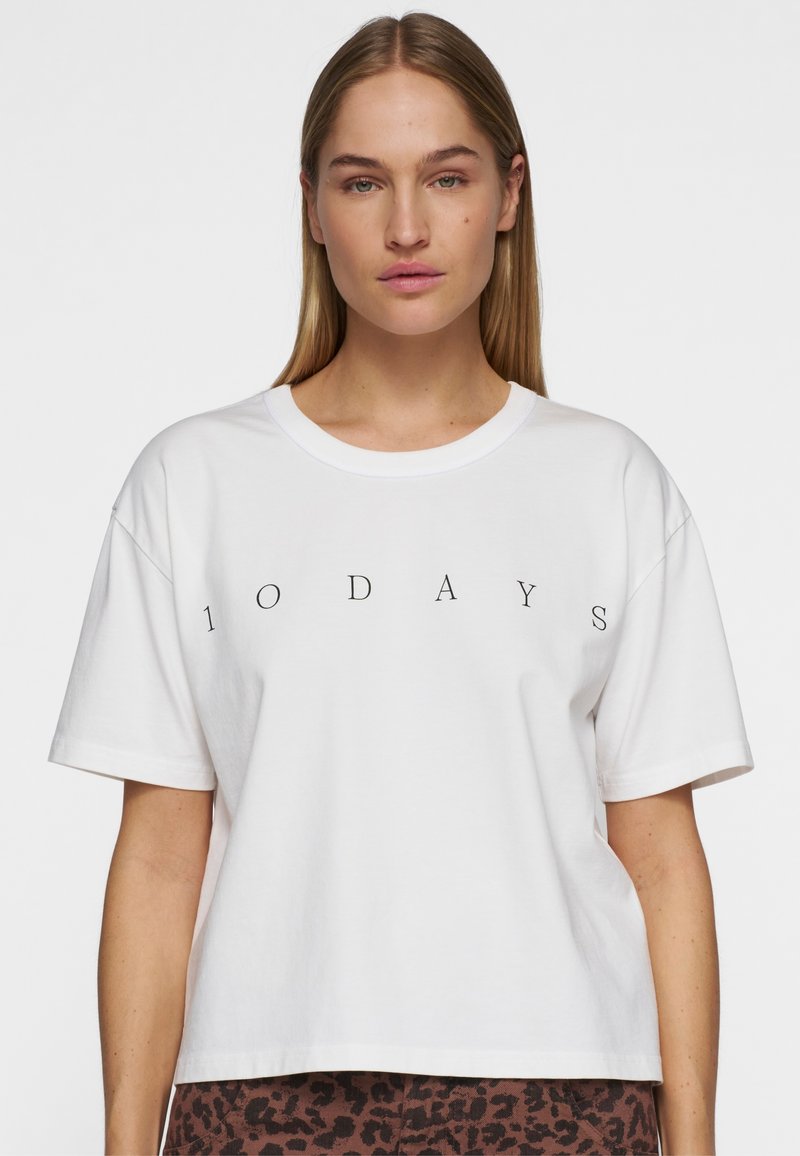 T-shirt bianco in cotone con colletto tondo e maniche corte, con il testo "10 DAYS" stampato in nero sul petto.