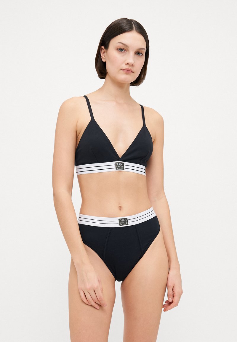 Svart bikini-sett med trekantet bralette med tynne stropper og matchende høytalende bunn. Hvitstripet midjebånd med logodetalj.